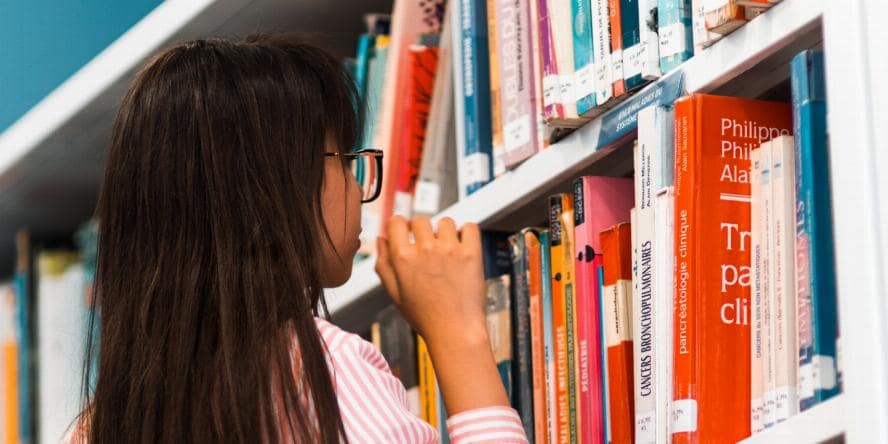 woman wearing pink shirt in front of bookshelf